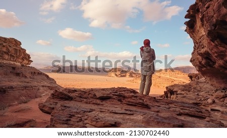 Young woman standing on rocky ground in desert landscape, view from behind. Wadi Rum, Jordan