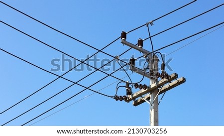 High-voltage cable connections on poles. Details of electrical wiring and transmission lines in insulators on concrete sleeves on a blue sky background. Selective focus