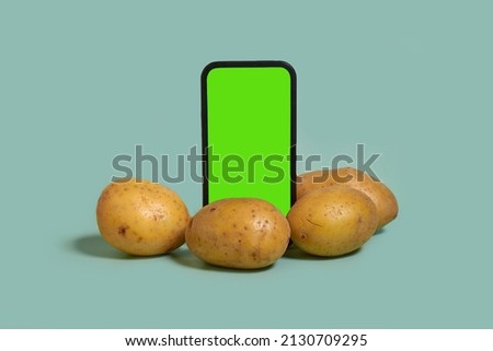 Online shopping. Smartphone with a chromakey screen and potatoes on a blue background