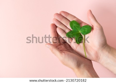 A four leaf clover in male's hands on a pink background. Good for luck or St. Patrick's day. Shamrock, symbol of fortune, happiness and success. Holding good luck in hands. Make a wish. Copy space. Royalty-Free Stock Photo #2130720182