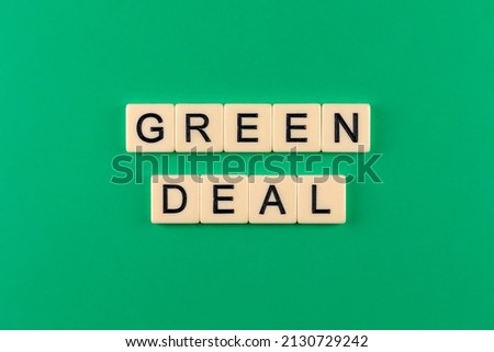 Sentence "green deal" composed of letters put on the green background. Photo taken under artificial, soft light