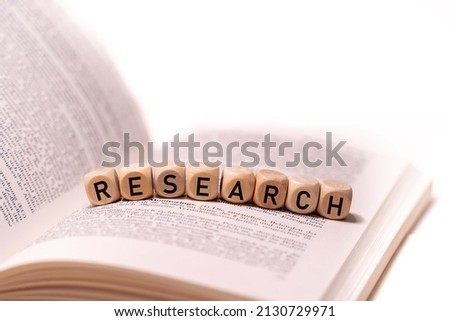 the word RESEAECH spelled on an open book with wooden letters, concept picture with white background