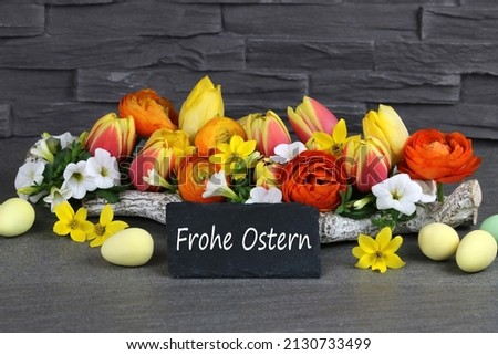 Flowers , Easter eggs and a chalk board with the text Frohe Ostern,translates to Happy Easter.