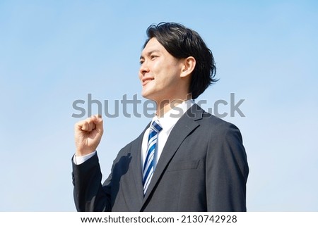 Asian businessman guts pose gesture in clear sky