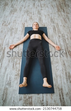 A girl lies on a yoga mat. Girl in the Shavasana pose.Conscious relaxation of body and mind. Do yoga lying on the floor. High quality photo Royalty-Free Stock Photo #2130744758