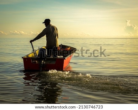 Silhouette of a fishermen on boat with outboard motor boat ready to fishing during beautiful sunrise at Labuan island, Malaysia. Royalty-Free Stock Photo #2130746723