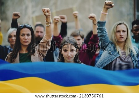 Crowd of activists protesting against Russian military invasion in Ukraine walking in street. Royalty-Free Stock Photo #2130750761