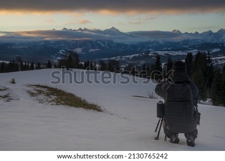 Photographer taking pictures of mountain landscape in winter