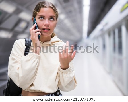 Young european female with mobile waiting the metro on the subway station platform