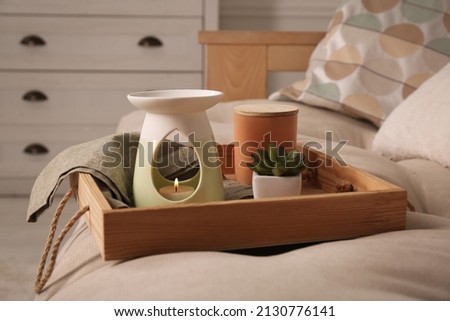 Tray with stylish aroma lamp and houseplant on sofa in room Royalty-Free Stock Photo #2130776141