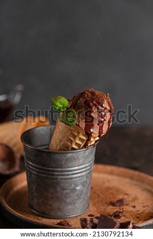 Homemade chocolate ice cream cone with chocolate syrup and mint, vertical photo
