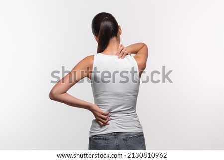 Unrecognizable long-haired brunette woman with neck and back pain rubbing her painful body, lady suffering from office syndrome, back view, white studio background, panorama with copy space Royalty-Free Stock Photo #2130810962