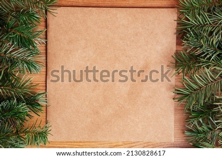 dark green lush pine fir branch frame on light brown wood and recycled brown paper background fir leaves. Christmas tree or holiday card design for eco-friendly natural products or chalet banner
