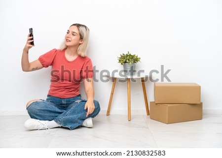 Young woman moving in new home among boxes isolated on white background making a selfie