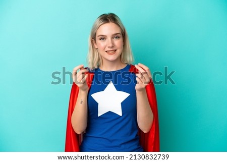 Super Hero caucasian woman isolated on blue background making money gesture