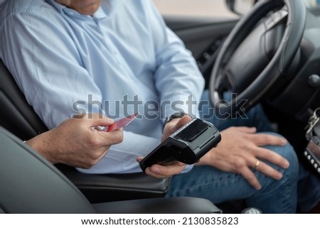 unrecognizable cab driver holding a bank payment terminal to process credit card payment purchases - transport concept, cab, taxi and technology Royalty-Free Stock Photo #2130835823