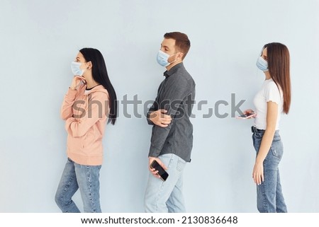 Three people standing together in the studio against white background.