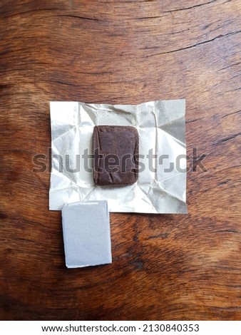 Close up vertical of an opened pack of beef stock cubes with silver foil paper wrappers on an old vintage wooden surface in the kitchen. simple lighting. space for copy text. for food articles and ads