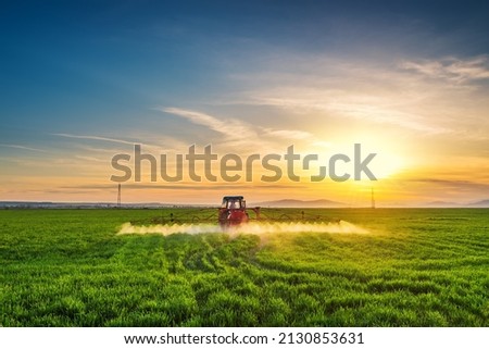 Tractor spray fertilizer spraying pesticides on green field, agriculture background concept. Royalty-Free Stock Photo #2130853631