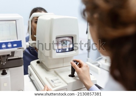 Doctor testing for eyes with special optical apparatus in modern clinic. Ophthalmologist examining eyes of a patient using digital microscope during a medical examination in the ophthalmologic office Royalty-Free Stock Photo #2130857381