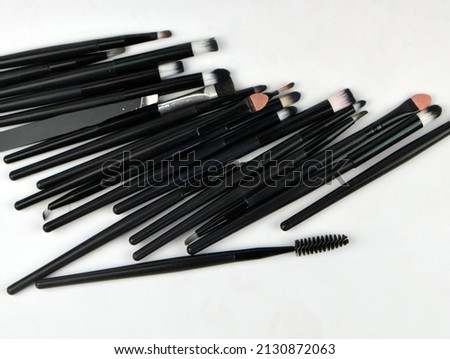 a lot of makeup brushes lie on a white background soft focus
