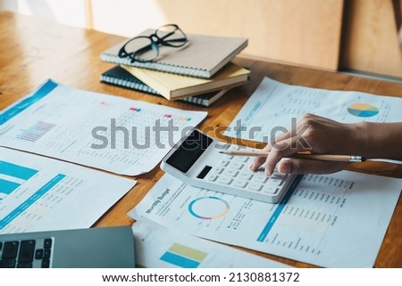 Close up of businesswoman or accountant hand holding pen working on calculator to calculate business data, accountancy document and laptop computer at office, business concept