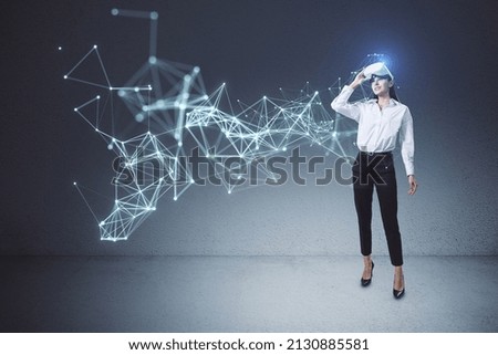 Attractive young european businesswoman with VR glasses using abstract polygonal network mesh hologram in concrete interior. Metaverse and AI concept