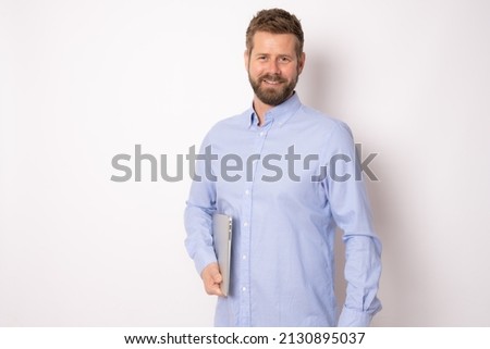 Smiling cheerful caucasian business man in glasses wearing classic shirt, standing with laptop isolated over white background. Business concept. Royalty-Free Stock Photo #2130895037
