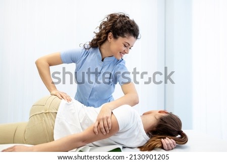 Young doctor chiropractor or osteopath fixing lying womans back with hands movements during visit in manual therapy clinic. Professional chiropractor during work Royalty-Free Stock Photo #2130901205