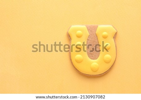 Tasty gingerbread cookie in shape of horseshoe for St. Patrick's Day celebration on green background
