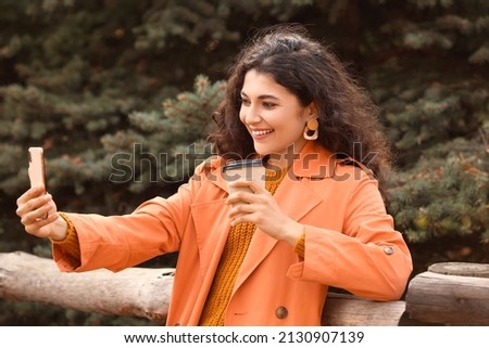 Beautiful woman drinking tea and taking selfie outdoors