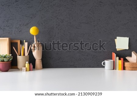 Creative desk with notebook, desk objects, office supplies, books, and cactus on a dark blue background.	
