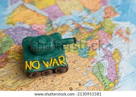 A plasticine tank on the background of a world map, as a symbol of peace and goodness. There is no war appeal. Stop war.