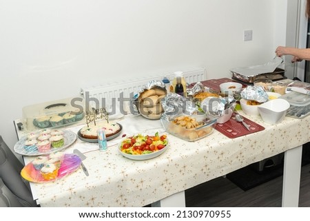 Party food laid out on a table including salad, buns, cake, and sausage rolls and bread rolls.