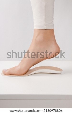 Medical insoles. Isolated orthopedic insoles on a white background. Treatment and prevention of flat feet and foot diseases. Foot care. Insole cutaway layers. Leg hanging over the insole. Royalty-Free Stock Photo #2130978806