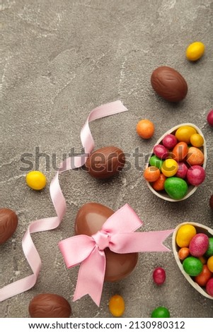 Chocolate Easter eggs with pink ribbon on grey background. Vertical photo. Top view