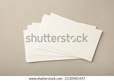 Blank white business cards on grey paper background. Mockup for branding identity. Template for graphic designers portfolios.