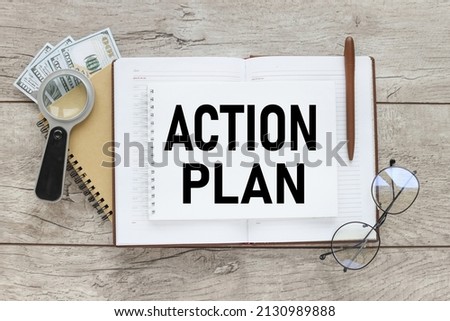 wooden background with open notepad with text. Action Plan