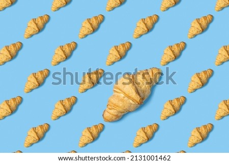 A croissant pattern on a minimal light blue background. Top view, flat layout, modern minimalistic image concept