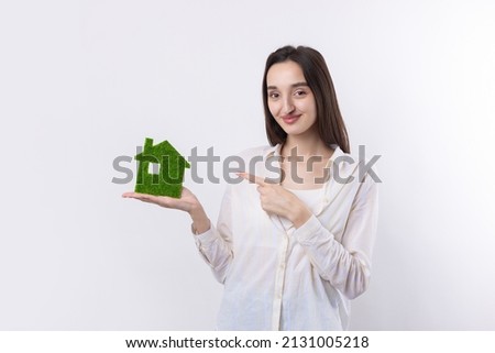 A young girl realtor holds a model of a green house in her hands. Sale of ecological real estate.