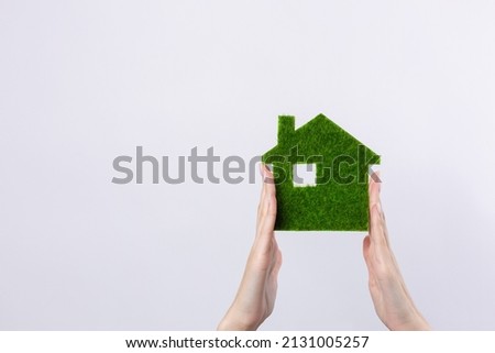 Female hands hold a model of a green house close-up. Sale of ecological real estate of the future.