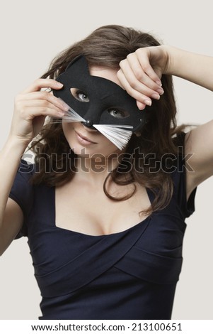 Portrait of a young woman wearing cat mask over gray background