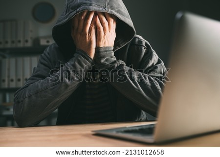 Regretful computer hacker covering face with hands in front of laptop, selective focus Royalty-Free Stock Photo #2131012658