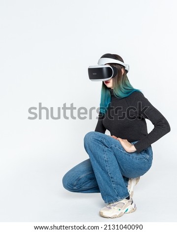 A teenager girl in a vr helmet plays in the virtual universe isolated on a white background, vertical frame