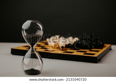 Hourglass and chessboard on a grey background. Strategy, management or leadership concept