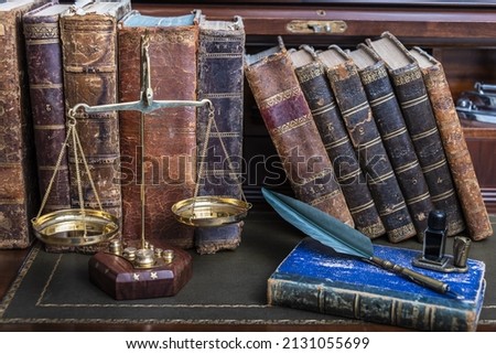 Scales of justice with law books on table of notary public in office.