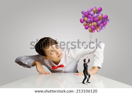 Businesswoman looking from under the table at businessman miniature