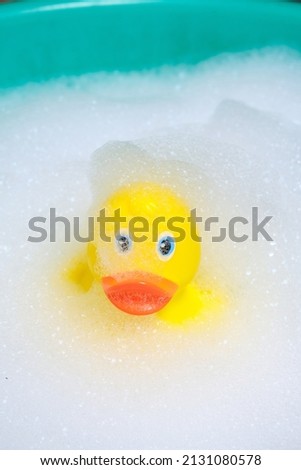 Yellow rubber duckling in bathroom filled with soap foam