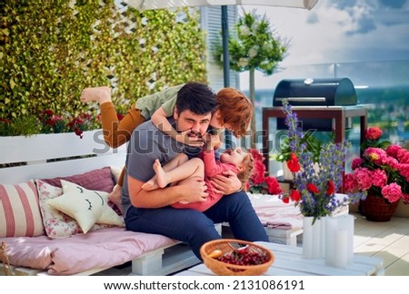 happy family, father and kids having fun, playing together on the rooftop patio on summer day