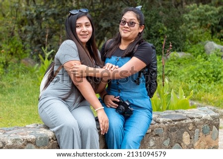 
two girls chatting sitting in a park, one frightened with her eyes, indicate advertising, business, sale,